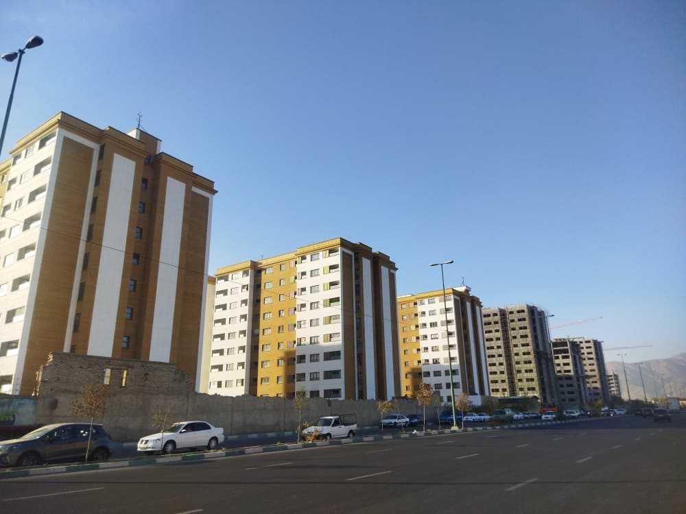 ردیف بلوک‌های تکمیل‌شده با نمای سفید و خردلی زیر آسمان آبی