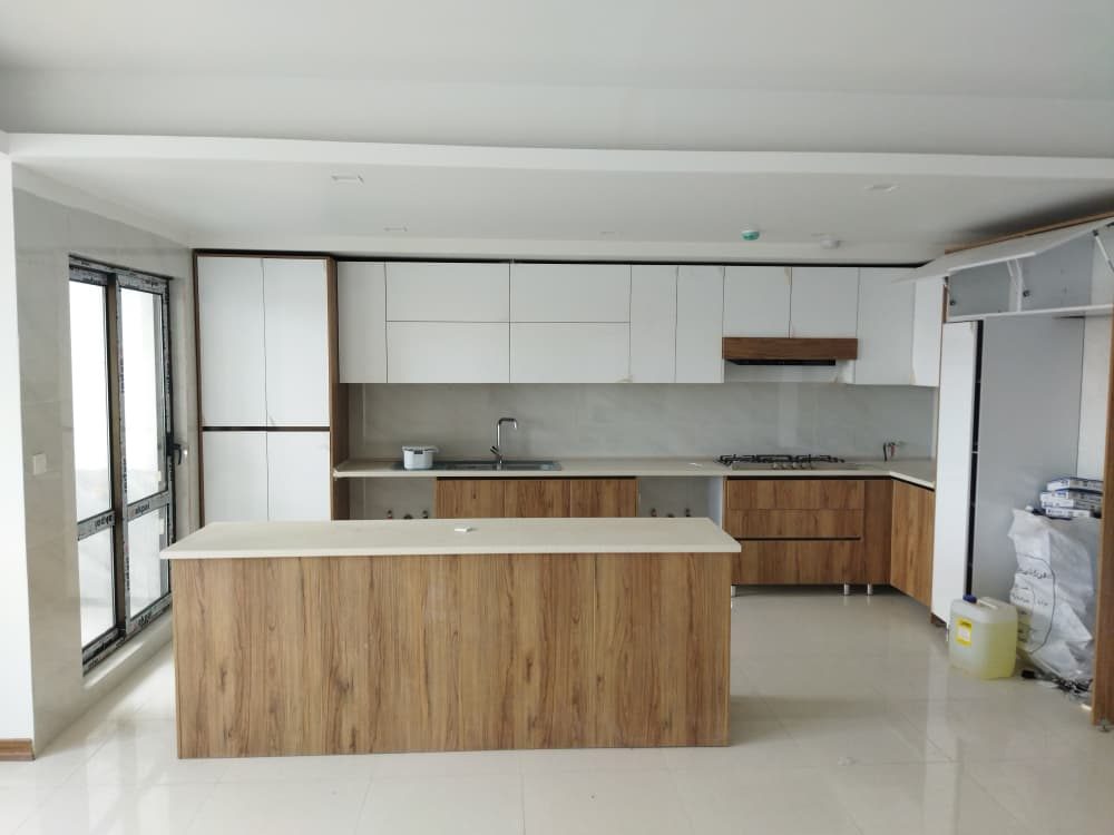 آشپزخانه با جزیره و کابینتهای سفید و چوبی