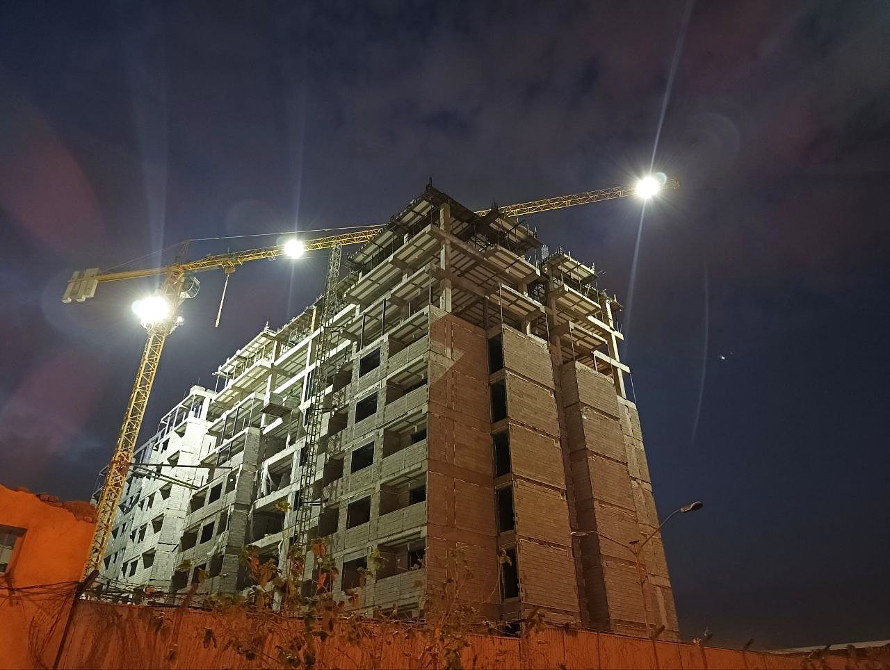 بلوک در حال ساخت زیر نور پروژکتور جرثقیل در شب